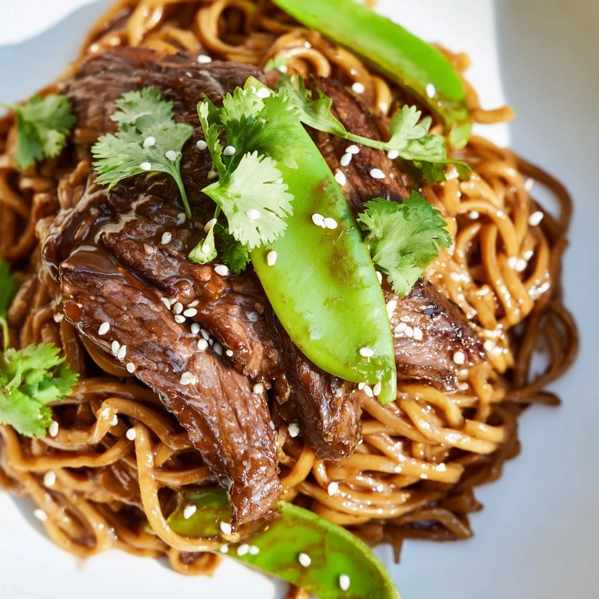 A close-up of Spicy Beef Noodles, highlighting colorful bell peppers, carrots, and sesame seeds on a rustic wooden table.