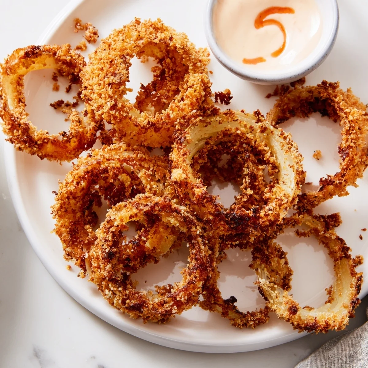 Freshly fried Crispy Onion Rings with Spicy Mayo Dipping Sauce beside a cold craft beer on a rustic table.  