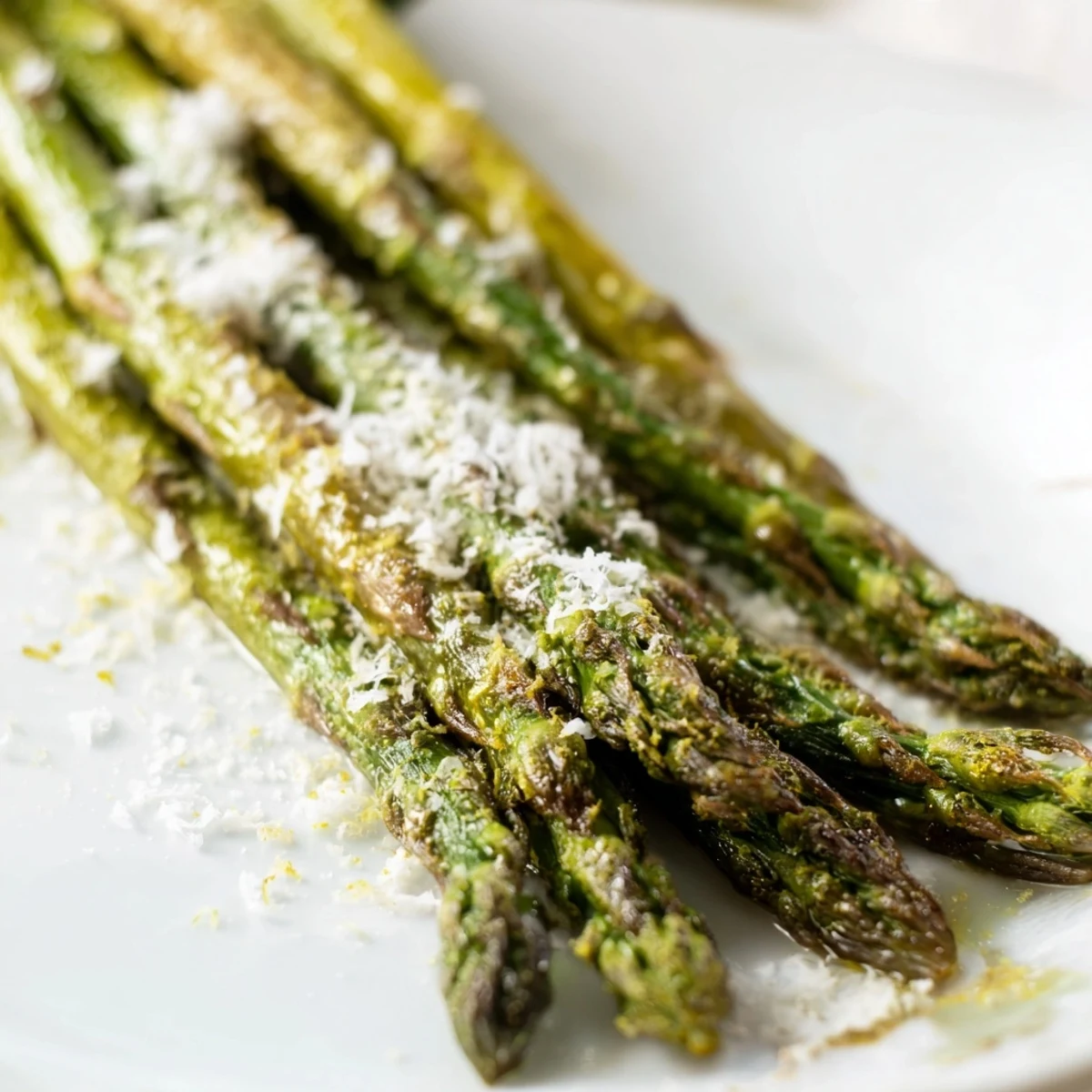 Golden roasted asparagus with Parmesan and lemon, sprinkled with salt and pepper on a parchment-lined sheet for an easy, elegant side.
