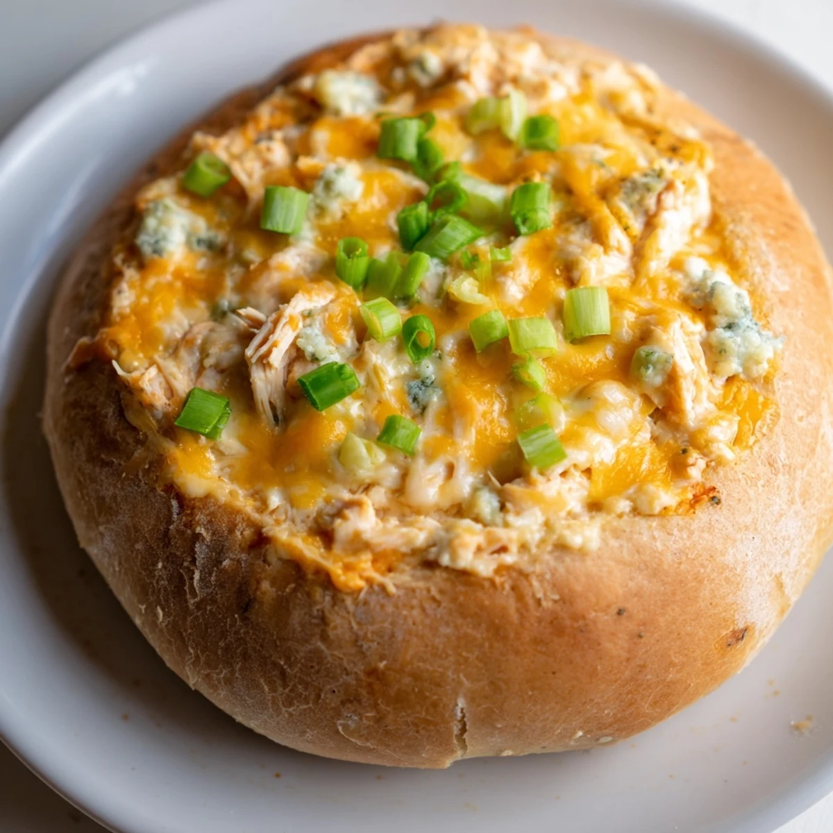 A bowl of Tailgate Buffalo Chicken Dip served with celery sticks, carrot sticks, and tortilla chips.