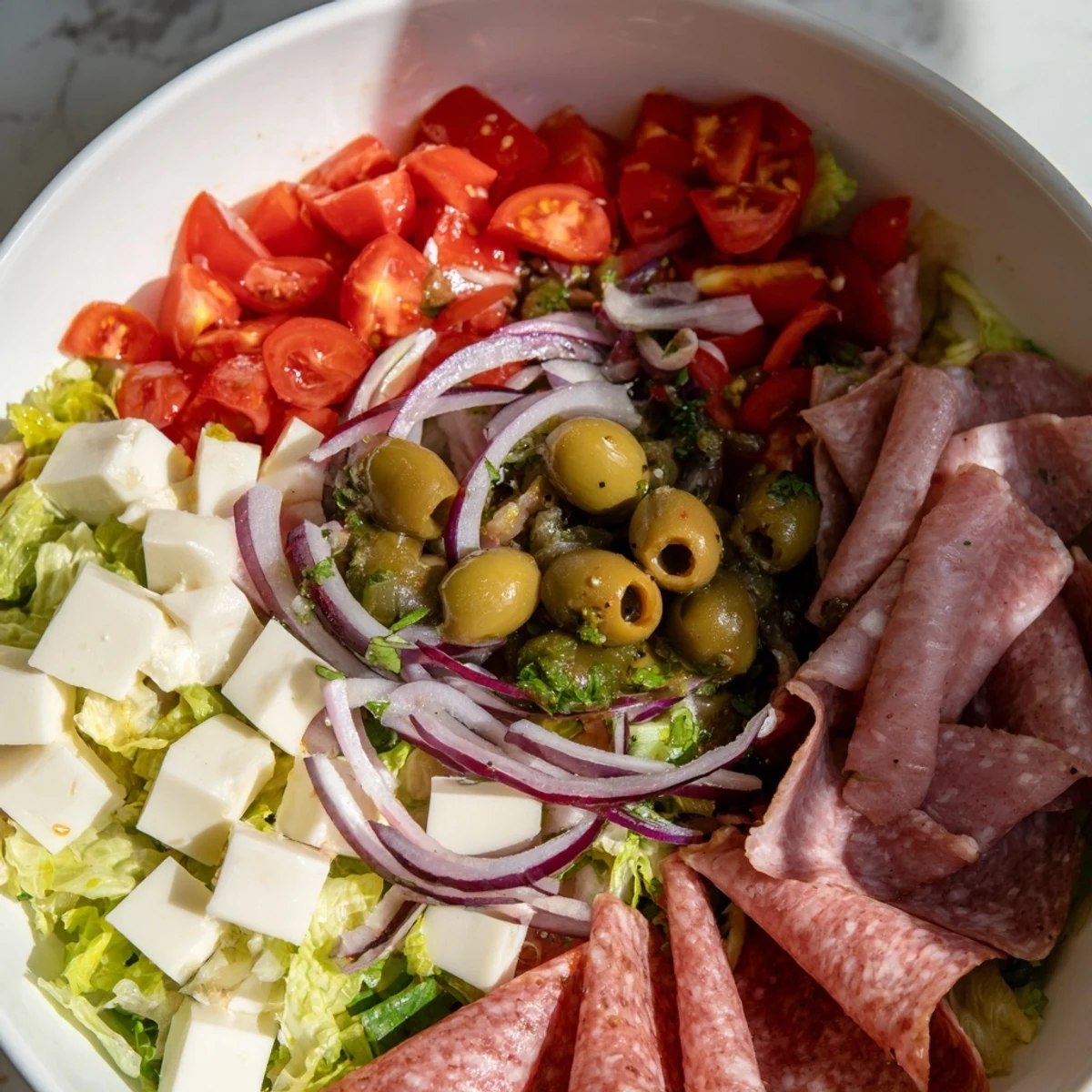 Hearty New Orleans Muffuletta Salad plated with cured meats and tangy olive relish, perfect for a gluten-free lunch.