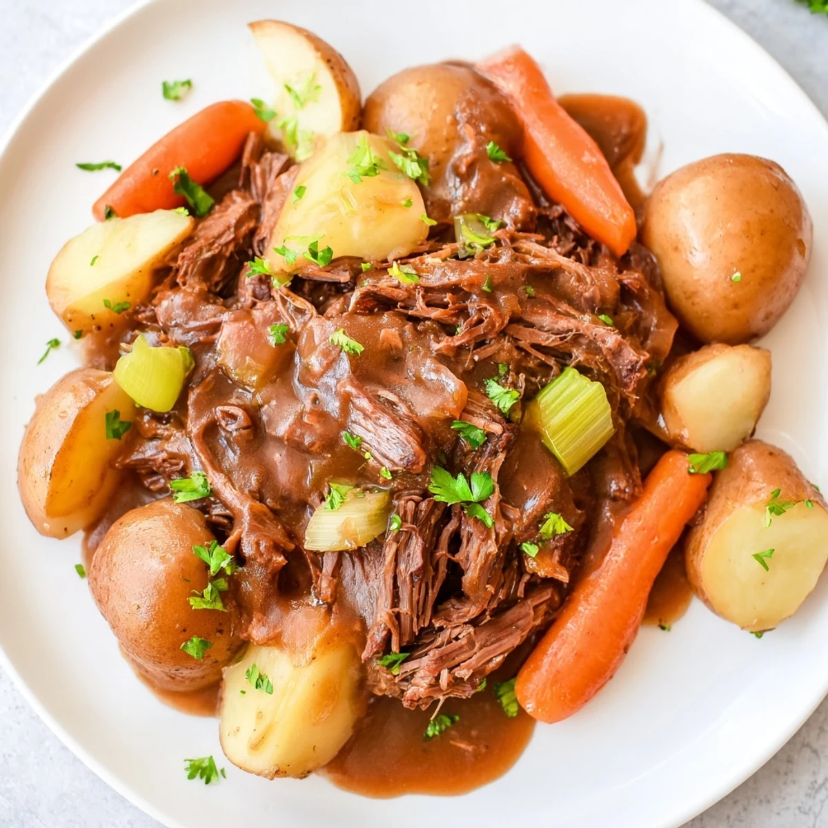 Golden Irish Beef Pot Roast, shredded and spooned over root vegetables, garnished with fresh parsley and ready to serve.