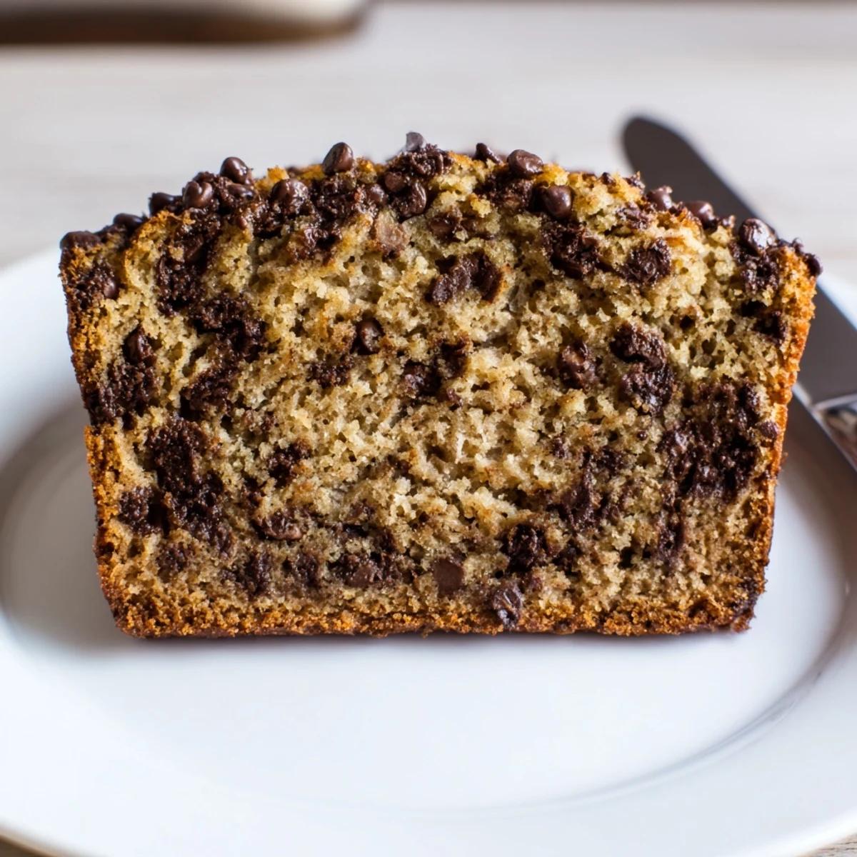 Warm chocolate chip banana bread loaf with a tender crumb, perfect for dessert or snacking.