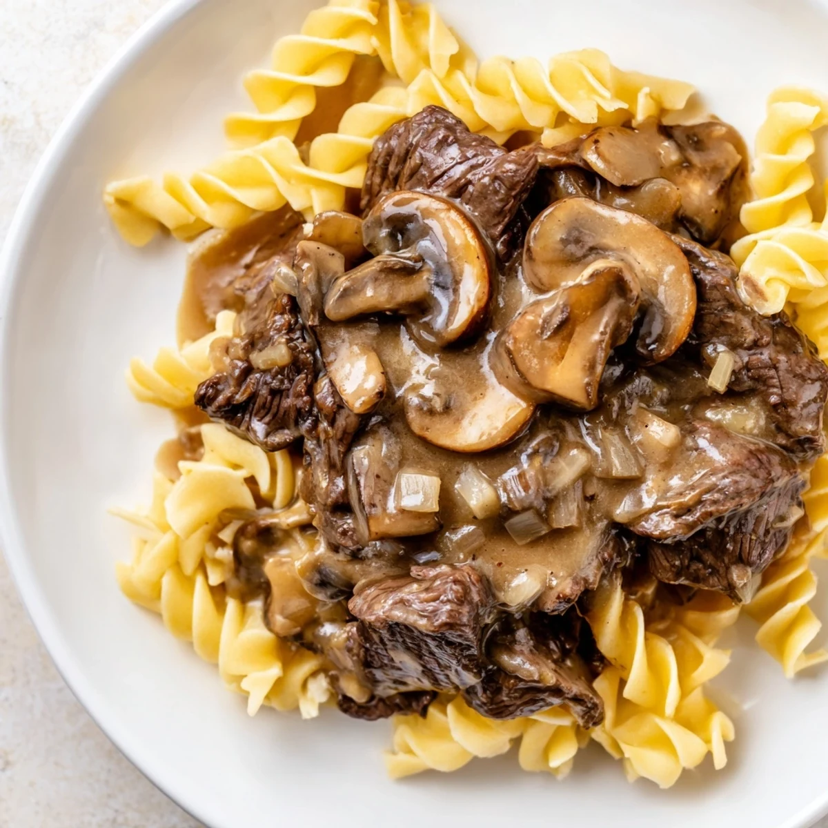 Close-up of Beef Stroganoff with Mushroom Gravy over egg noodles, highlighting juicy beef and rich gravy.