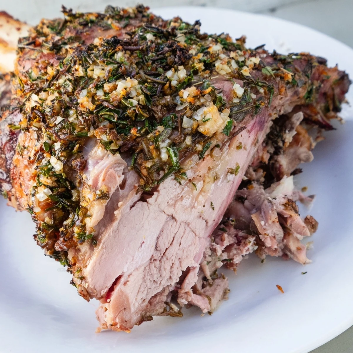Family-style platter of Roasted Lamb Shoulder with garlic-lemon crust, surrounded by caramelized vegetables and fresh herbs for a vibrant main dish.