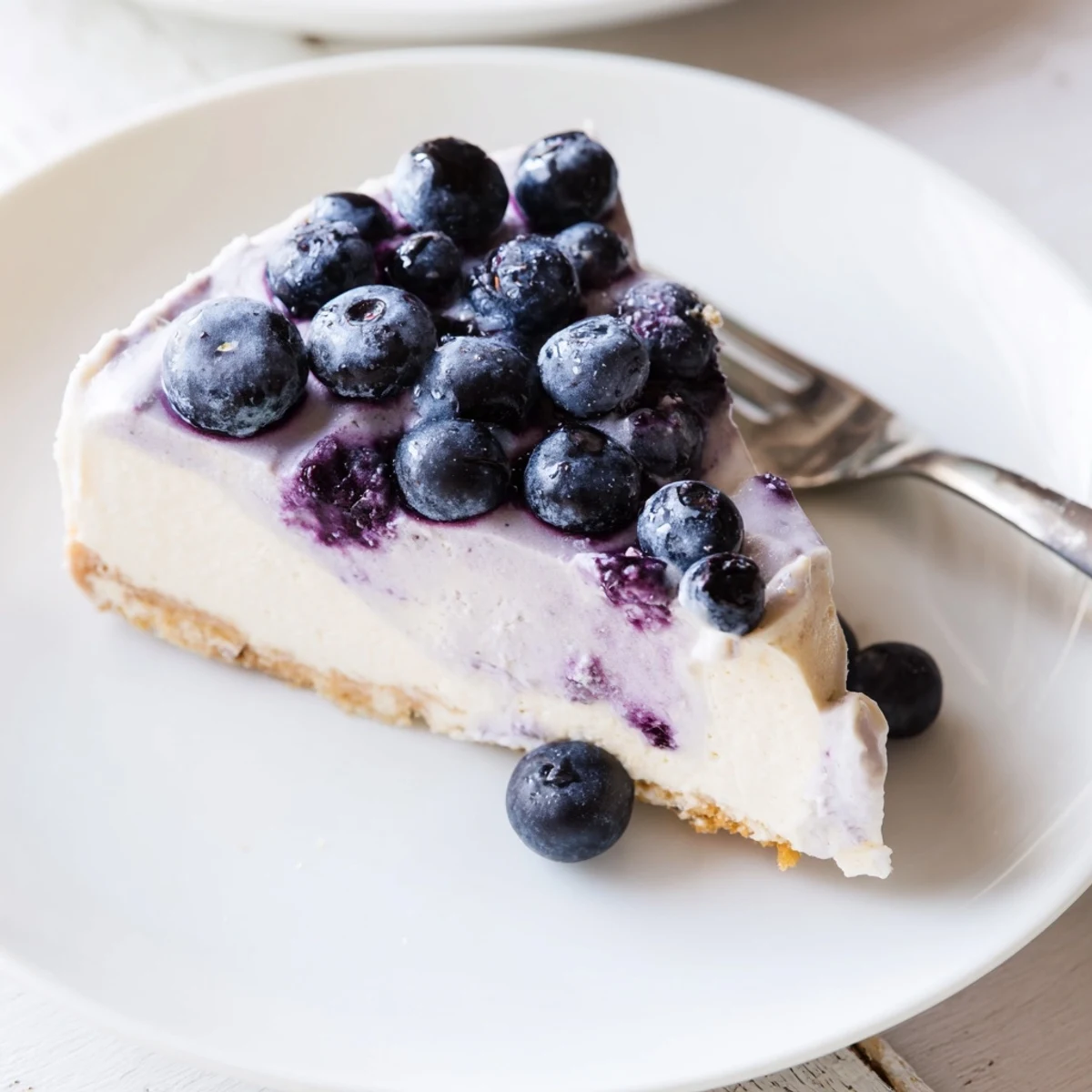 Homemade Blueberry Mousse Cheesecake topped with smooth mousse and a mint leaf garnish on a rustic wooden table.