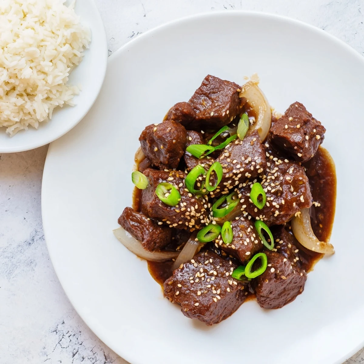 Steamed jasmine rice topped with tender Crock Pot Korean Beef and garnished with fresh green onions and sesame seeds.