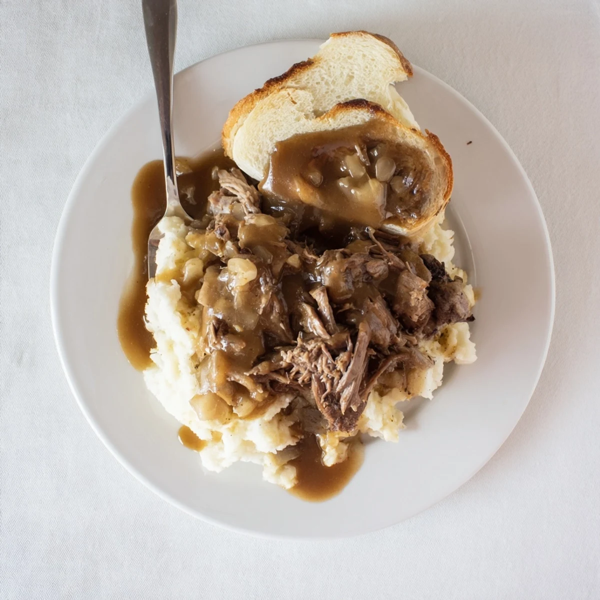 Slow Cooker Beef Manhattan serving tender beef piled on bread with mashed potatoes and ladled gravy for comfort.