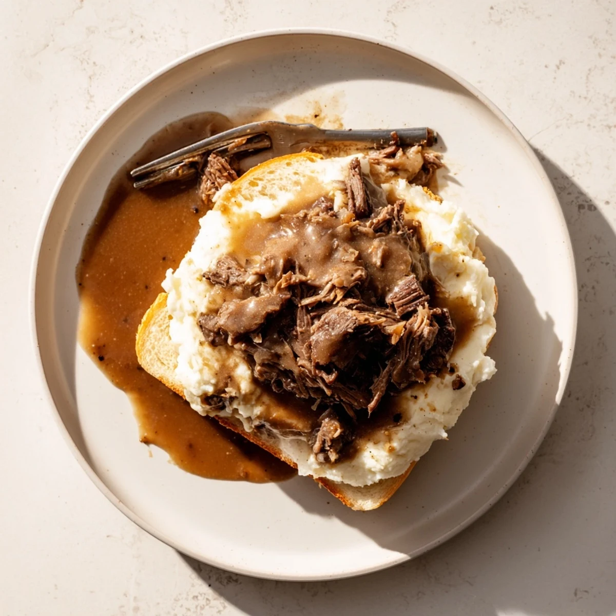 Hearty Slow Cooker Beef Manhattan plated with buttery mashed potatoes and savory gravy, perfect for a cozy dinner.