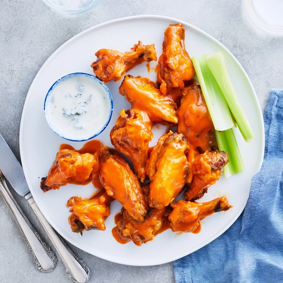 Savory crispy smoked buffalo wings with smoky aroma, presented with blue cheese dressing and celery on a wooden board.