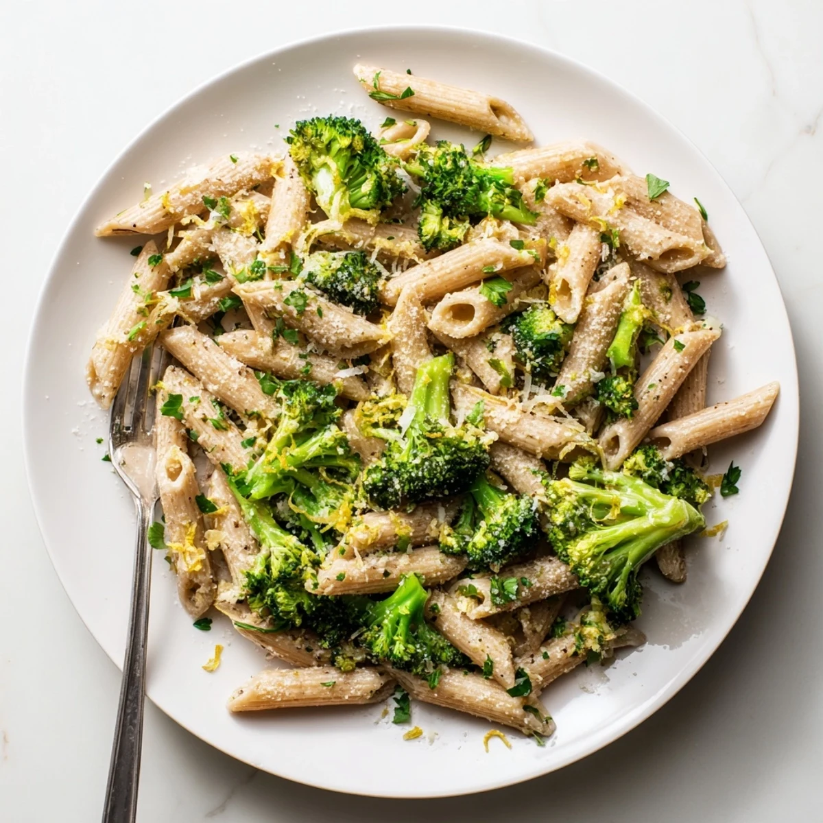 A serving of Easy Healthy Broccoli Pasta in a white bowl with extra parsley and red pepper flakes garnish.
