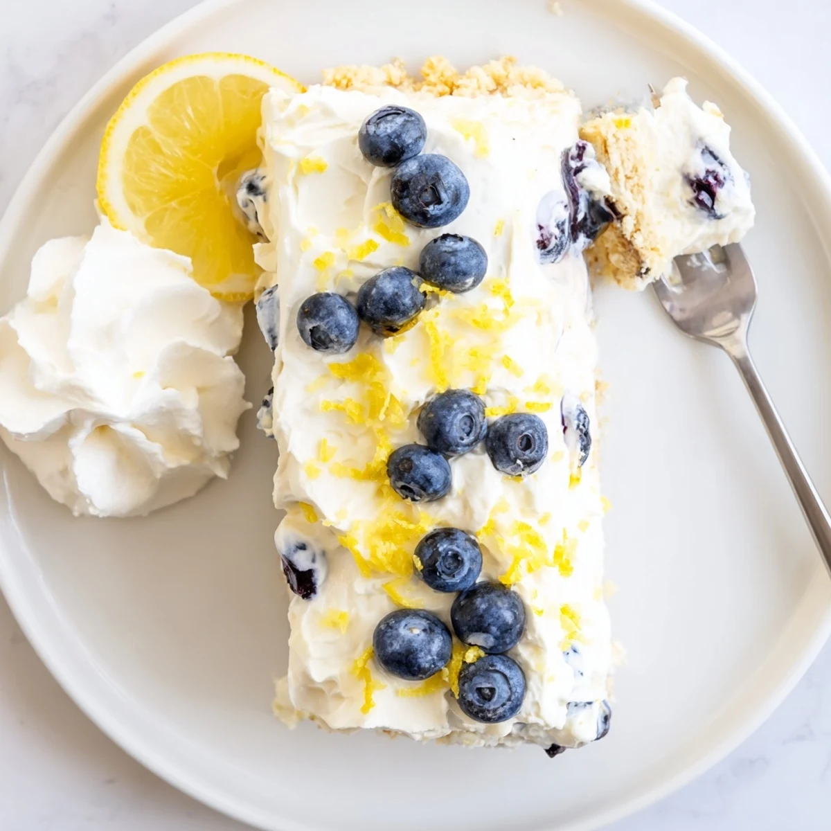Summer no bake lemon blueberry cream cake garnished with fresh blueberries and bright citrus zest