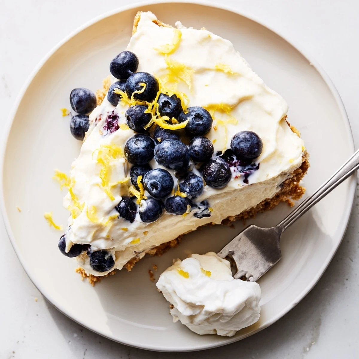 Creamy no bake lemon blueberry cake slice showing blueberry filling and whipped cream layers