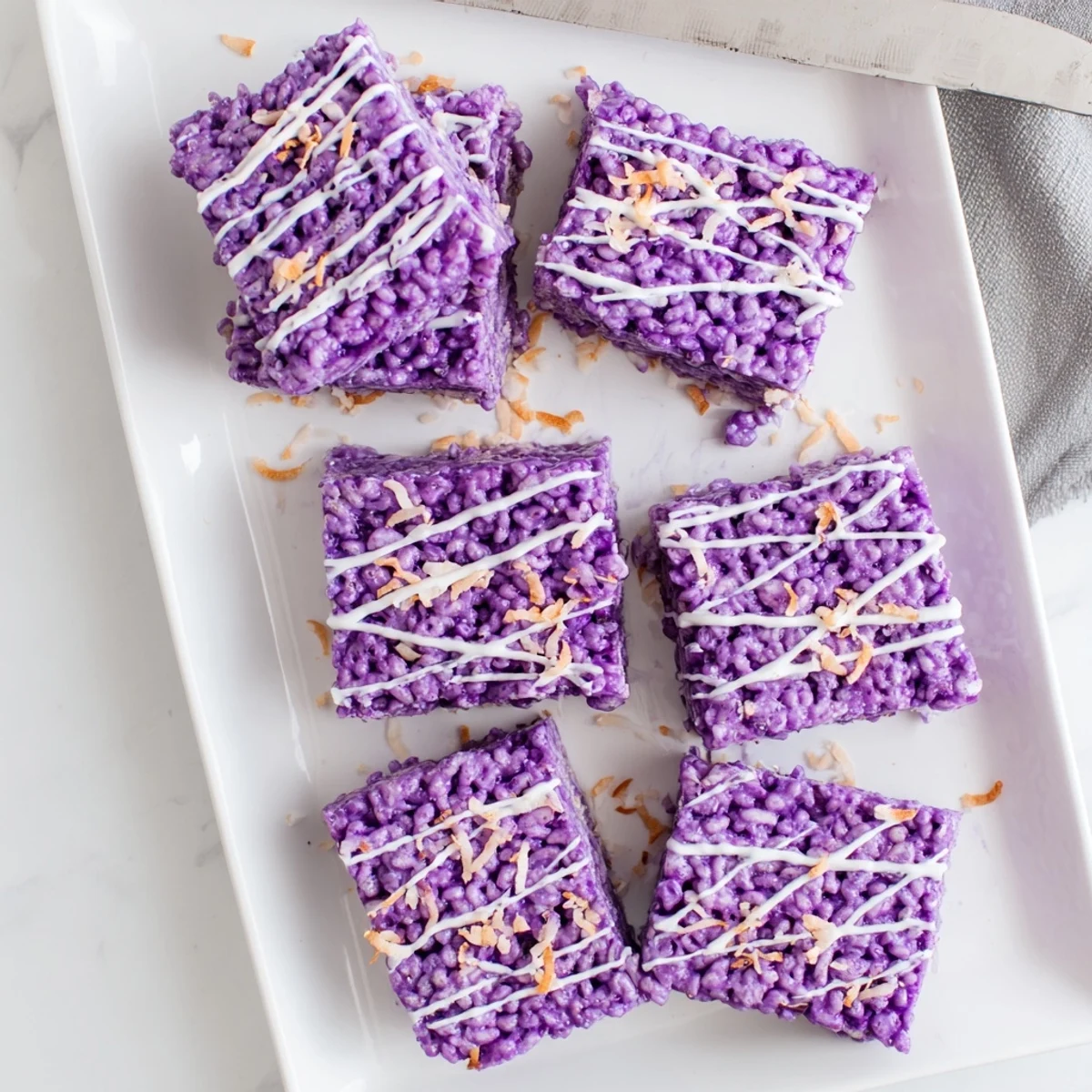 Vibrant purple Ube Rice Krispie Treats with melted white chocolate drizzle and toasted coconut topping