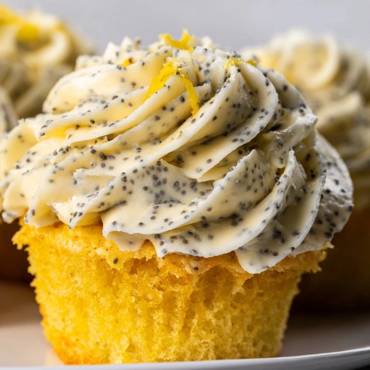 Golden lemon poppy seed cupcakes topped with swirls of creamy lemon cream cheese frosting