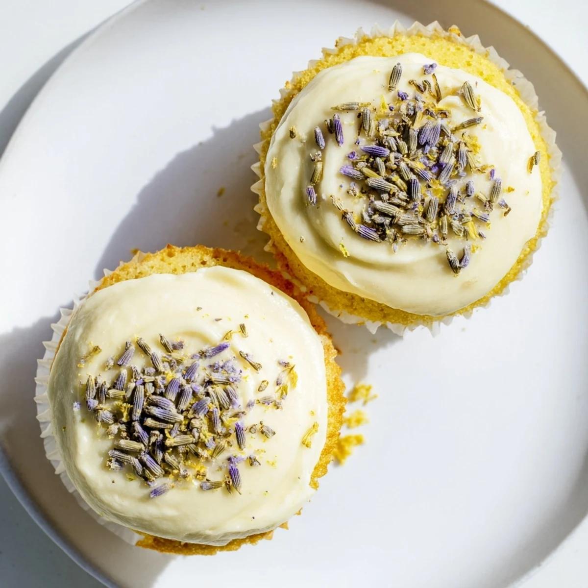 Golden lemon lavender cupcakes topped with creamy white frosting and fresh lemon zest garnish