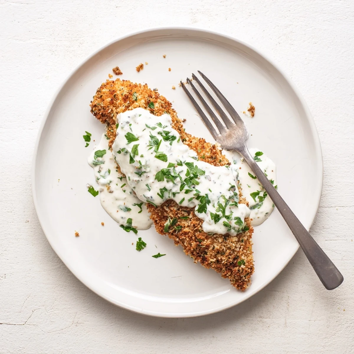 Juicy chicken breast with crunchy Parmesan coating swimming in a luscious white cream garlic sauce