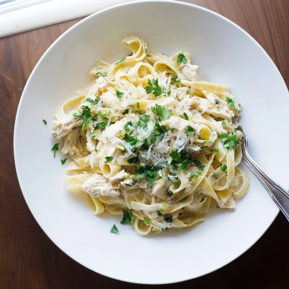 Slow cooker chicken Alfredo featuring tender shredded chicken and rich cheesy white sauce