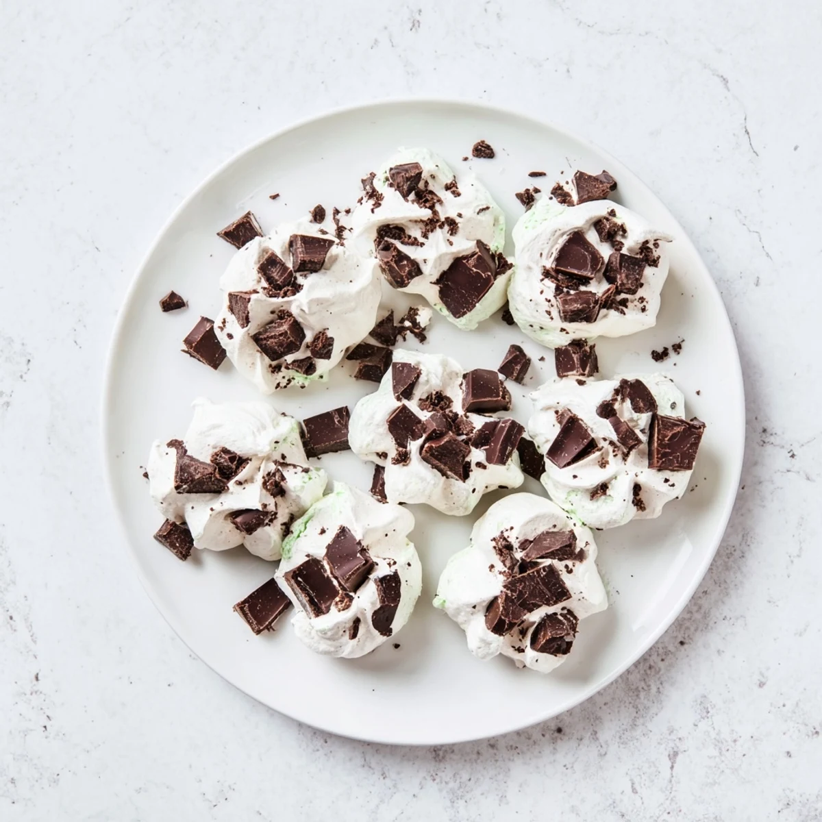 Dreamy dark chocolate and mint chip clouds arranged on a white baking sheet