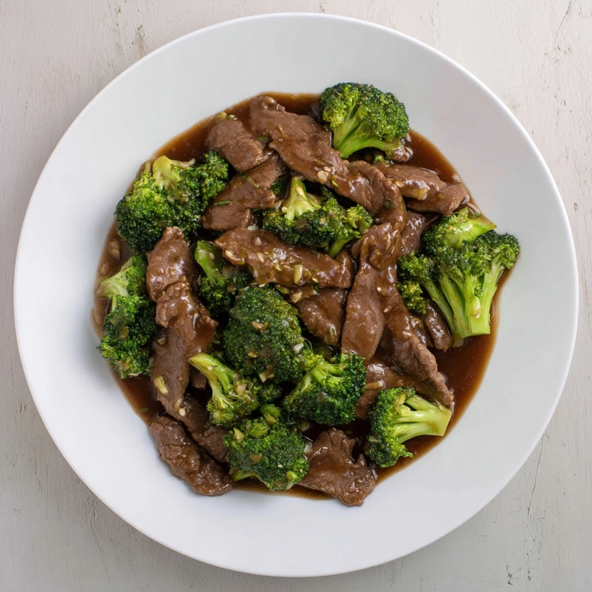 Rich glossy beef and broccoli stir fry sauce coats tender beef slices and crisp green florets in a dark savory glaze