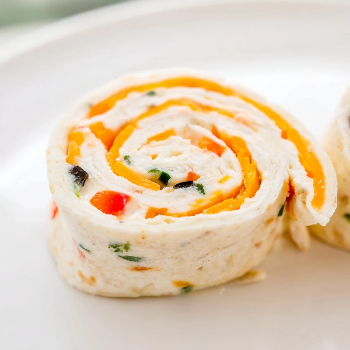 Bite-sized easy tortilla pinwheels sliced into rounds, revealing the savory cream cheese and cheddar studded with colorful vegetables inside