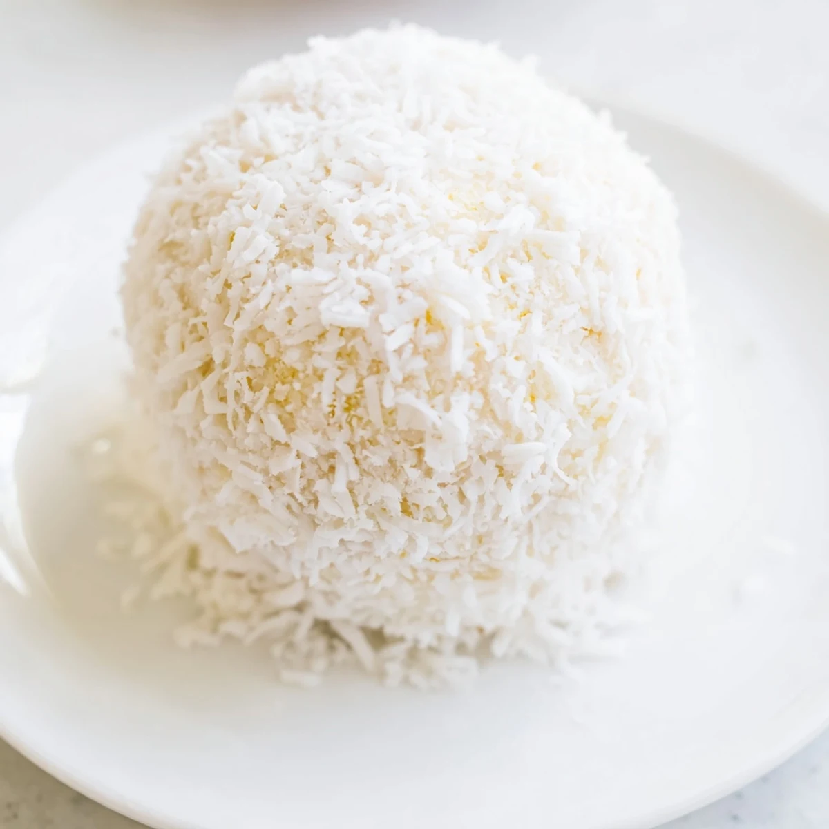 White no-bake Easter bunny coconut tails dusted with powdered sugar on a festive pastel platter