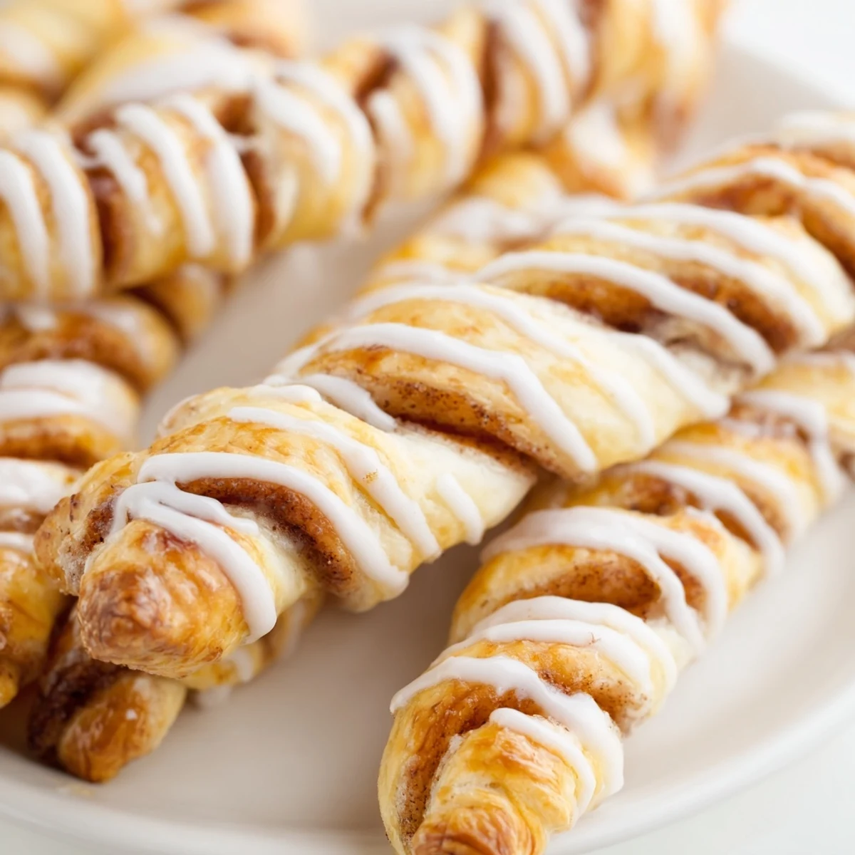 Soft glazed cinnamon twists arranged on a wooden board with sweet sugar coating visible