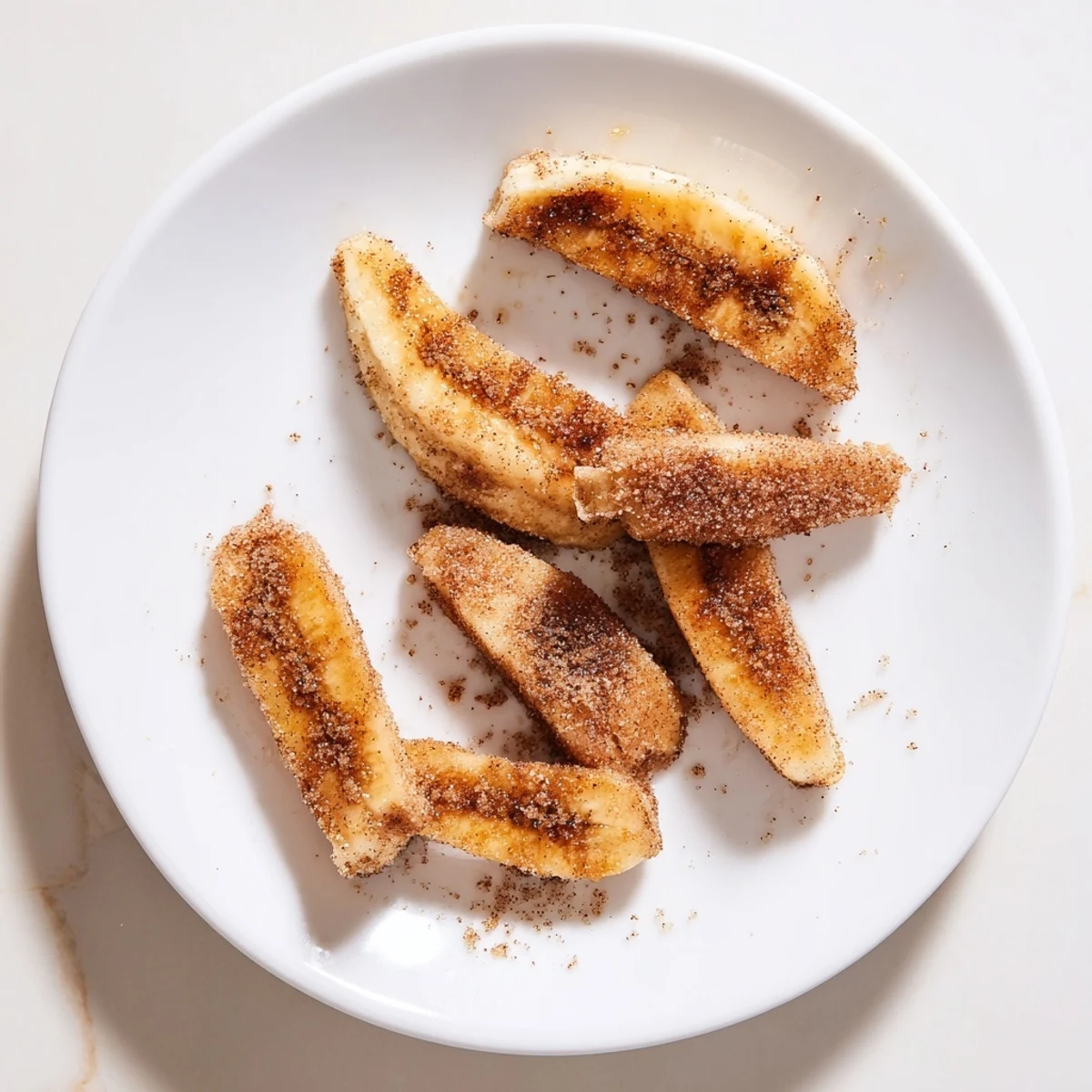 Golden brown pan fried cinnamon bananas caramelized in butter with brown sugar coating