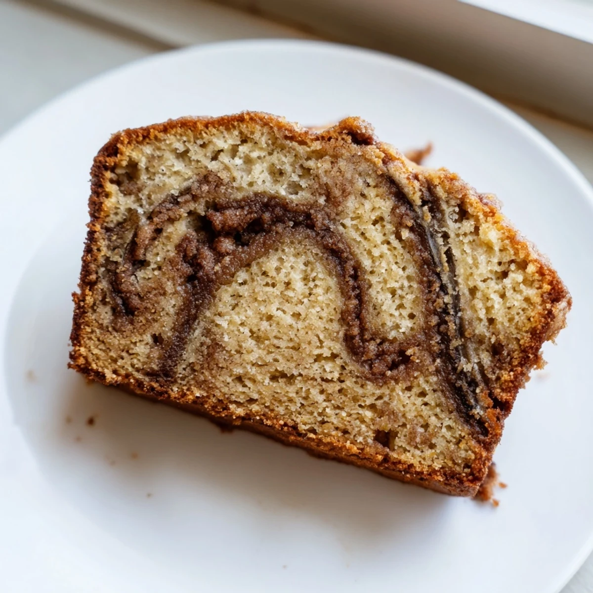 Warm slice of cinnamon sugar swirl banana bread showing marbled cinnamon ribbons inside