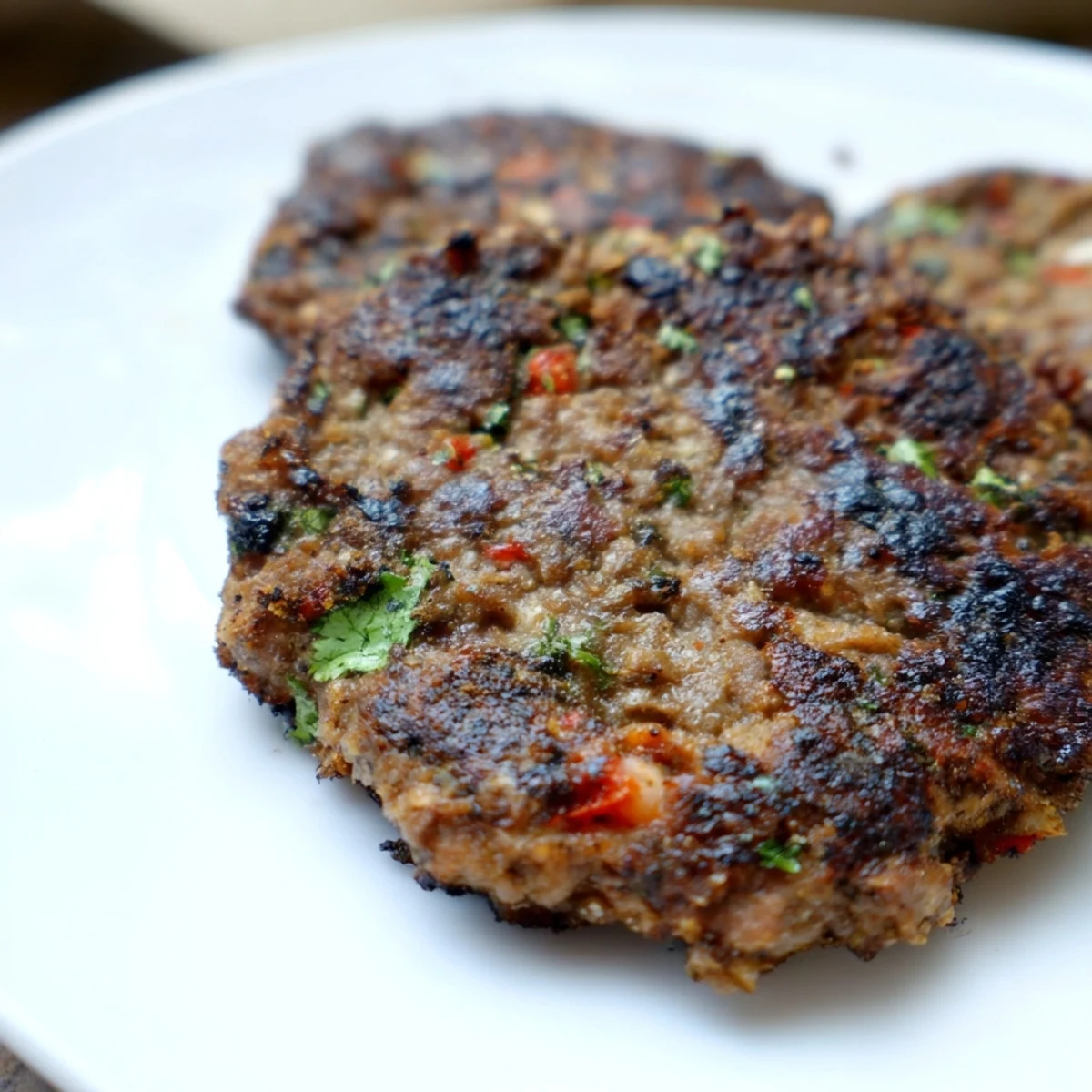 Golden Pakistani Chapli Kabab with crispy edges served alongside fresh mint chutney and warm naan bread