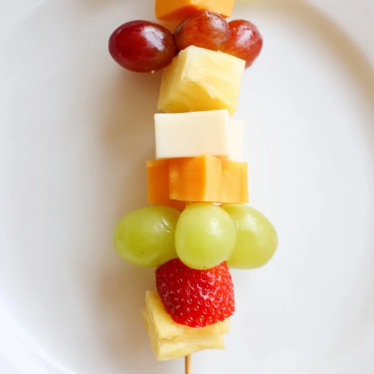 Colorful fruit and cheese kabobs arranged on platter with fresh mint garnish