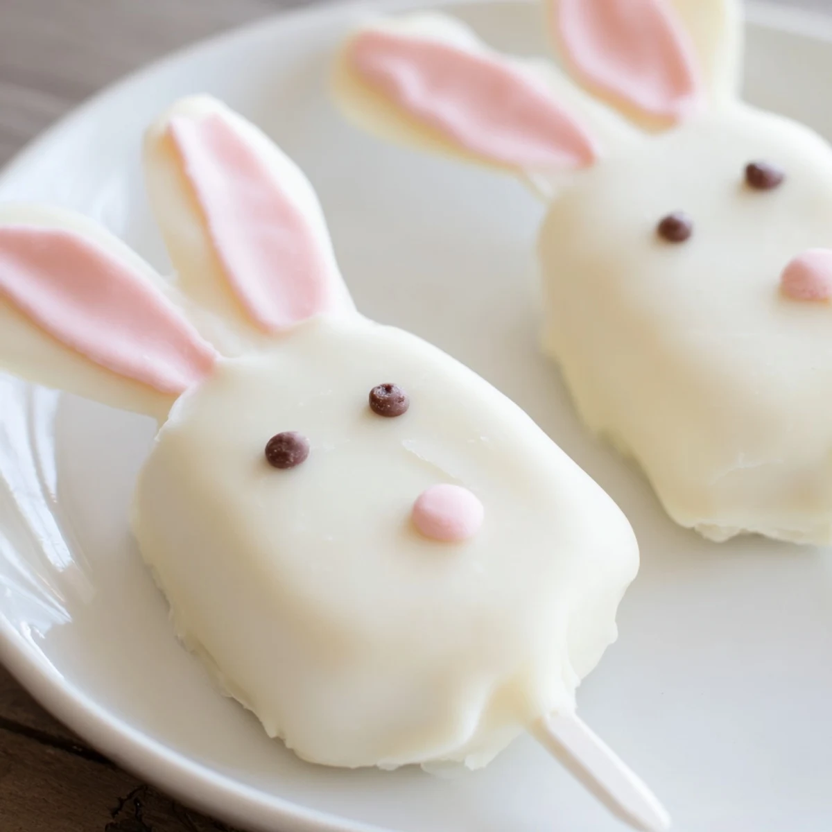 Adorable white chocolate bunny cakesicles with candy eyes and pink fondant ears on sticks