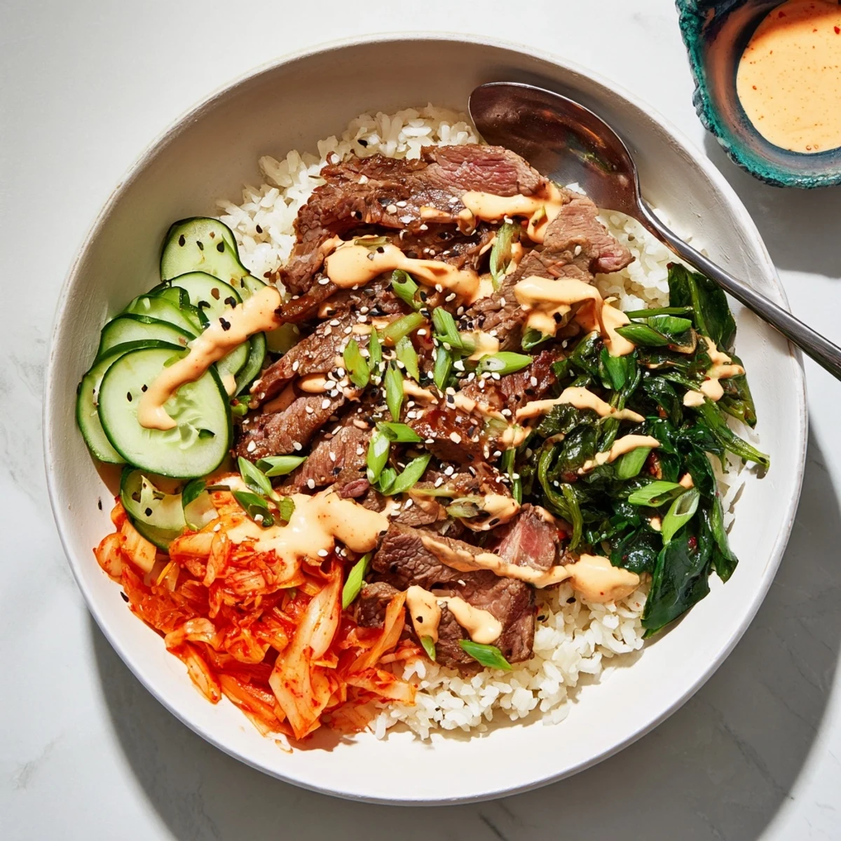 Caramelized marinated steak nestled in rice bowls with crisp veggies and creamy spicy drizzle