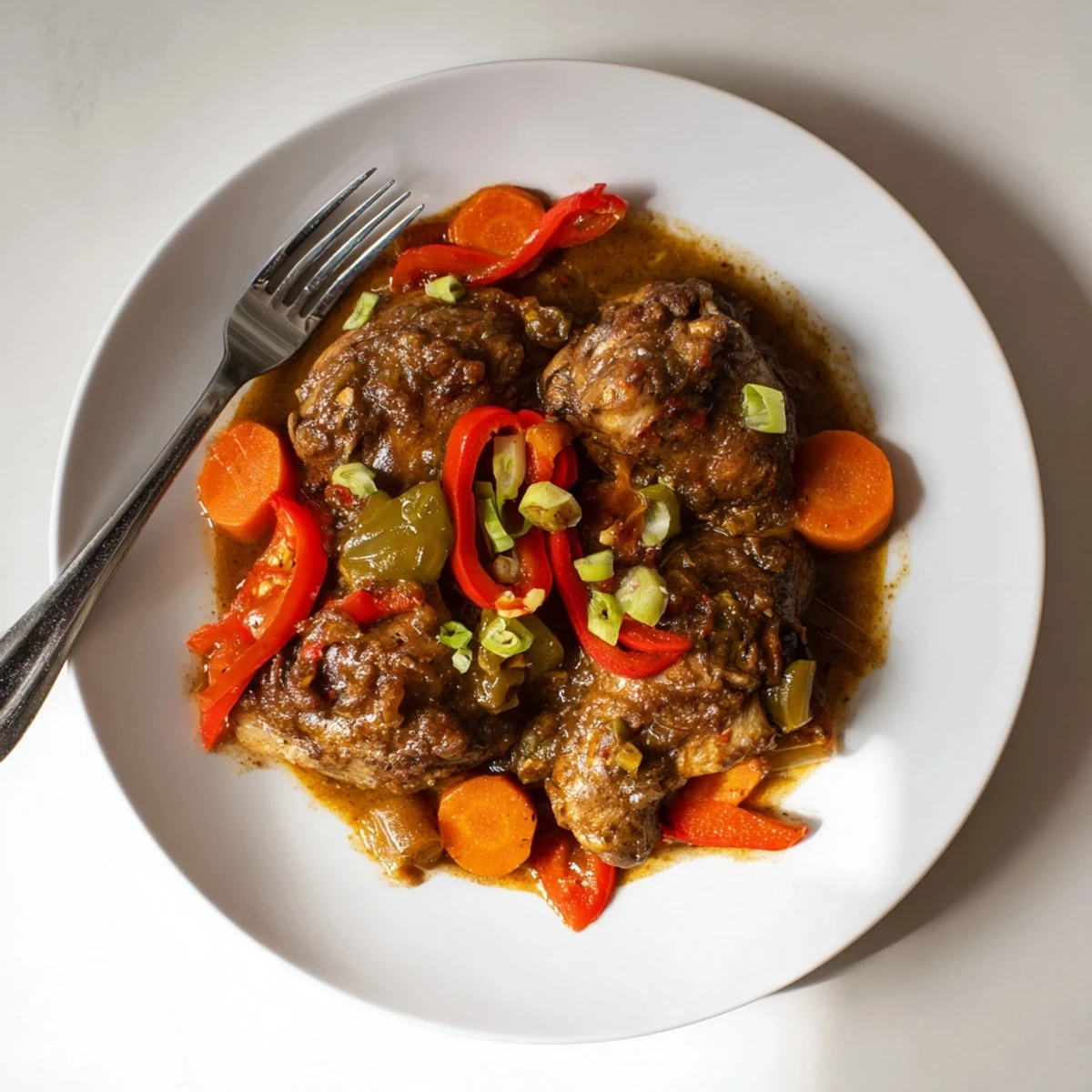 Golden seared Jamaican brown stew chicken with bell peppers and carrots in a thick savory sauce