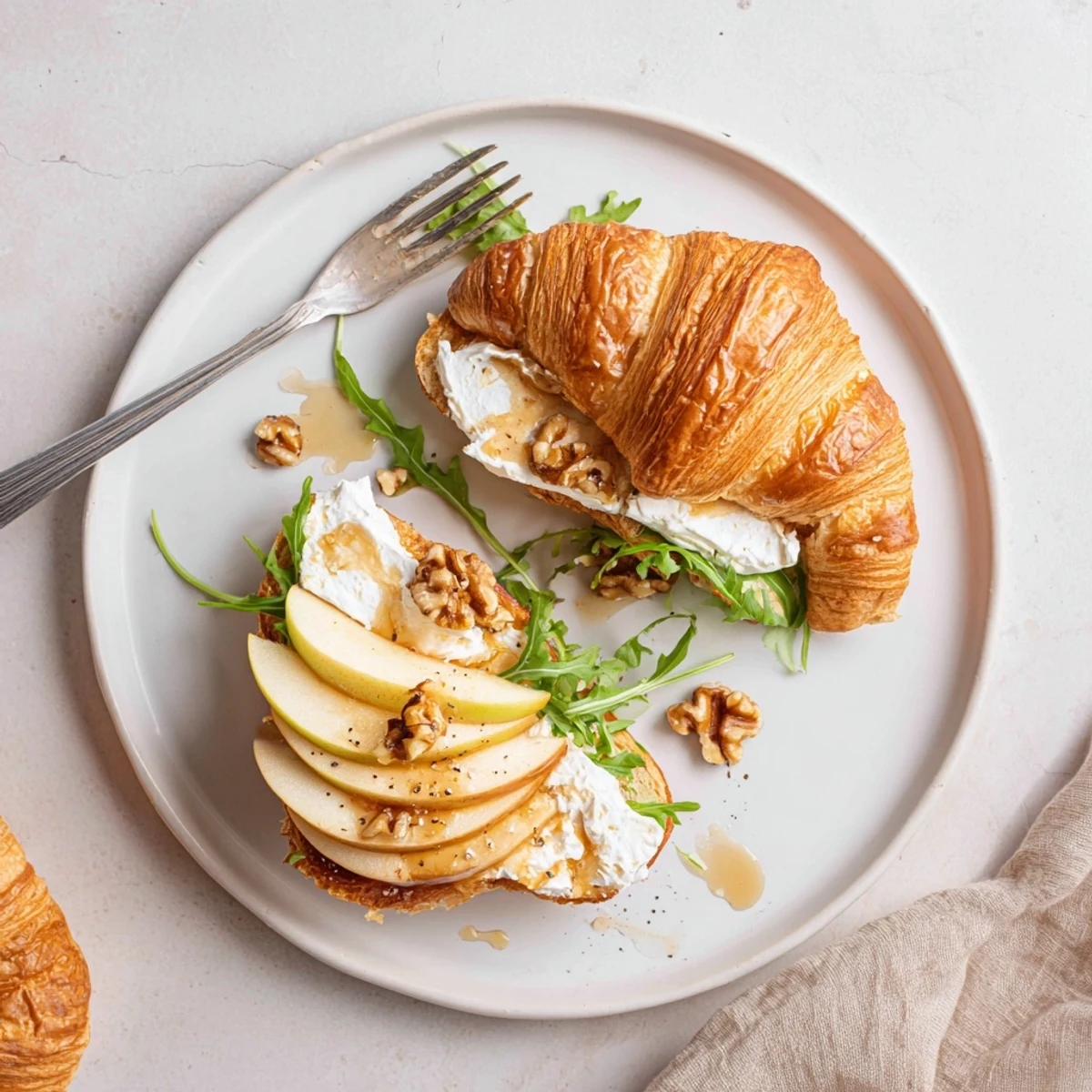 Buttery Apple Goat Cheese Croissant Sandwich layered with arugula, honey drizzle, crunchy nuts