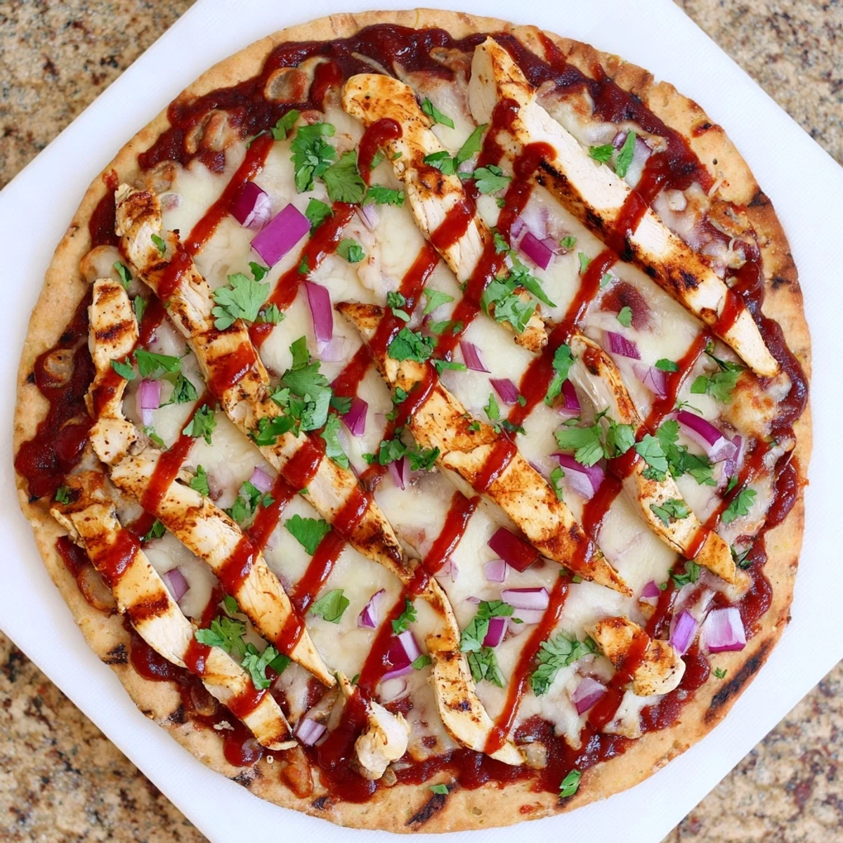 Golden grilled BBQ chicken pizza with melted mozzarella and red onions on a crisp crust