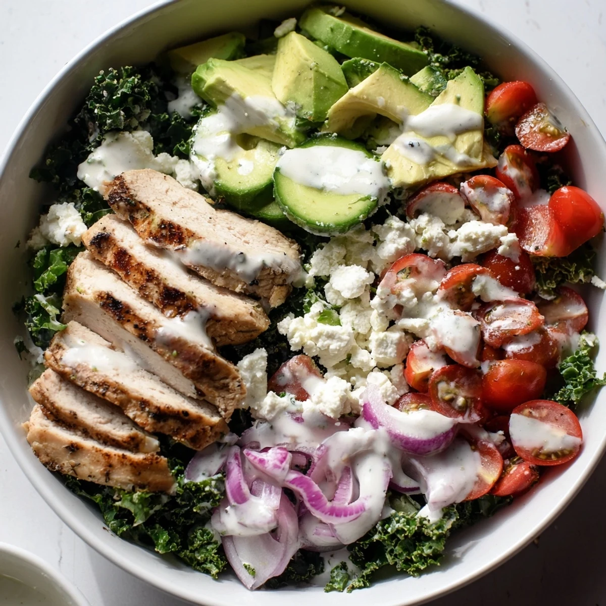 Colorful marinated kale and chicken bowl with fresh vegetables and creamy yogurt dressing