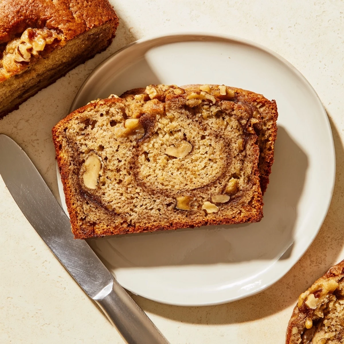 Golden banana nut bread loaf topped with chopped walnuts and swirled with cinnamon sugar