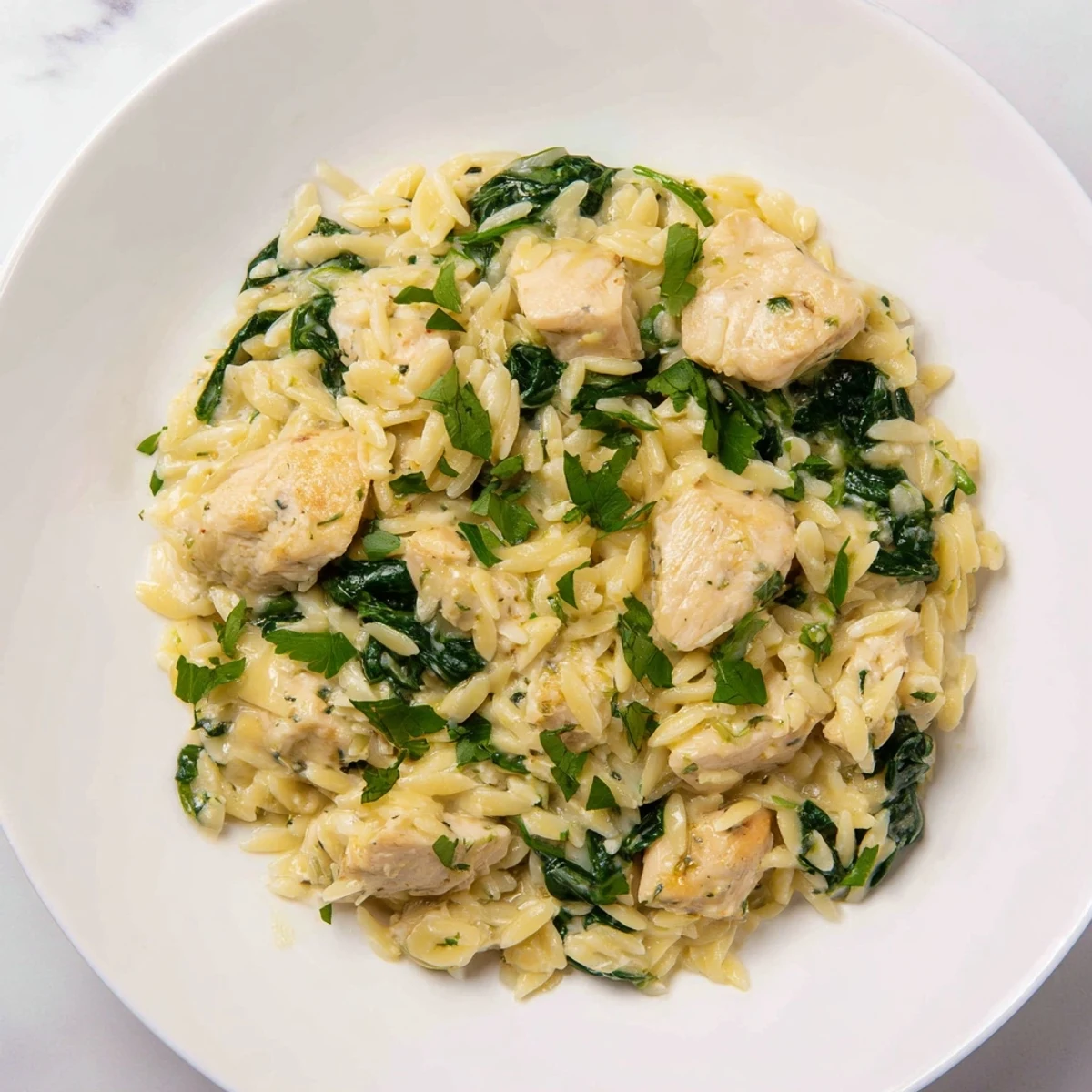 Creamy one pan Boursin chicken orzo with fresh spinach garnished with parsley
