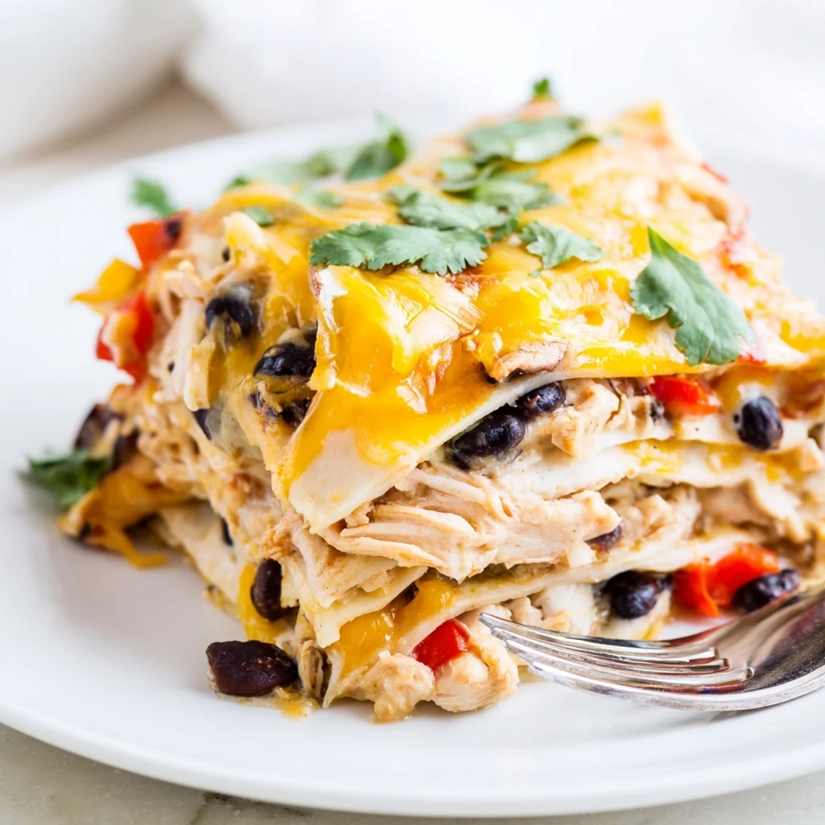 Creamy chicken taco lasagna casserole garnished with fresh cilantro on a white serving plate
