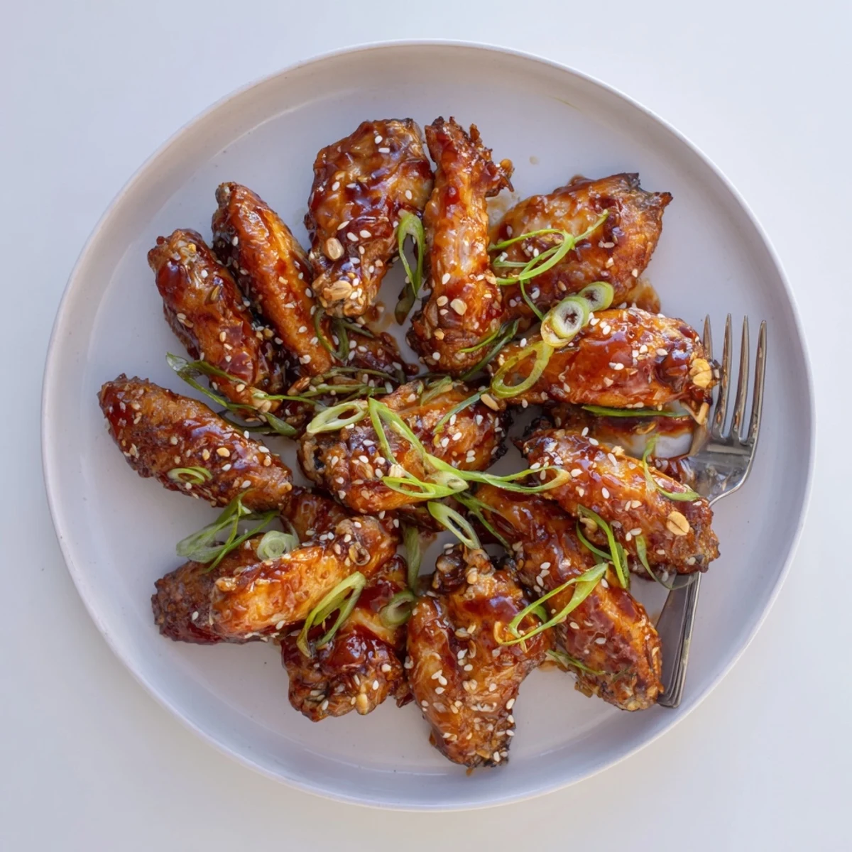 Crispy baked chicken wings coated in glossy sweet teriyaki sauce and garnished with fresh green onions