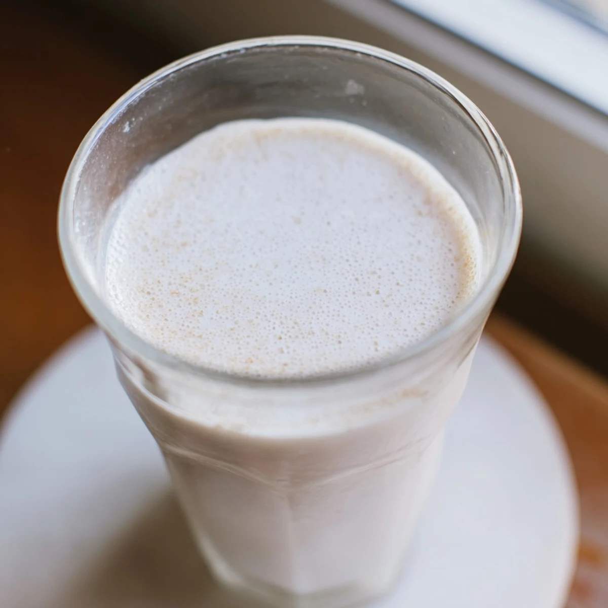 Creamy white almond milk in a glass pitcher with whole raw almonds