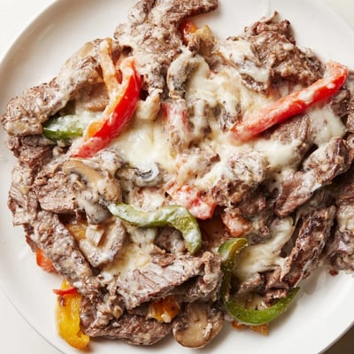 Creamy Keto Philly Cheesesteak Skillet sizzling in a skillet with tender beef and mushrooms.