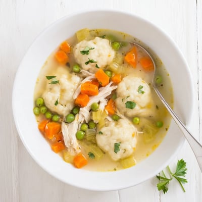 One Pot Chicken Dumpling Soup simmering in a pot with carrots and peas visible.