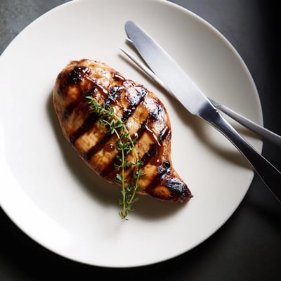 A delicious serving of Maple Dijon grilled chicken garnished with fresh thyme sprigs  
