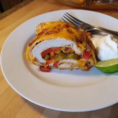 Golden brown baked chicken fajita roll ups garnished with fresh cilantro and lime wedges.